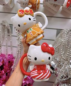 hello kitty mugs are being held by someone's hand