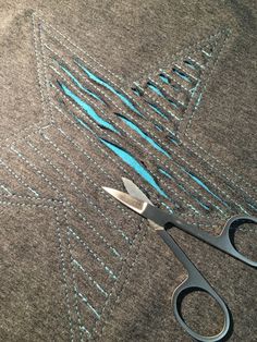 a pair of scissors sitting on top of a piece of fabric next to some stitching