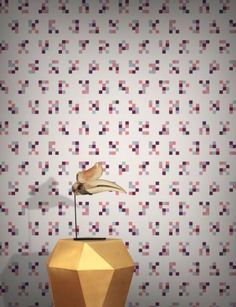 a small sculpture on top of a table in front of a wallpapered background