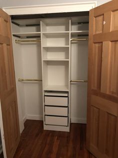 an empty closet with wooden doors and white shelving unit in the corner, next to hardwood flooring