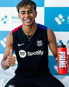 a young man holding a water bottle and giving the thumbs up