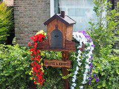 a wooden bird house with flowers around it