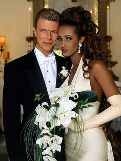 a man and woman dressed in formal wear posing for a photo with flowers on the bouquet