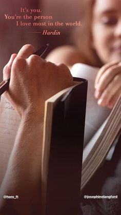 someone is writing on a book with a pen and paper in front of her face