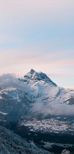 the mountains are covered in snow and clouds