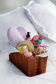 a basket filled with lots of items on top of a white bed covered in pillows