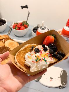 a person holding up a plate with pancakes and fruit on it in front of other plates