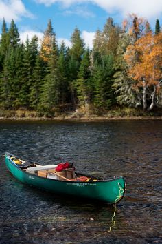 a man in a green canoe floating on top of a lake