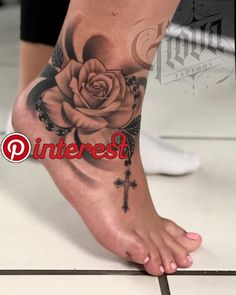 a woman's foot with a rose and cross tattoo on the top of it