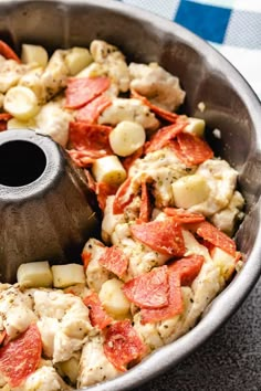 a pan filled with chicken and vegetables on top of a tablecloth next to a wooden spatula