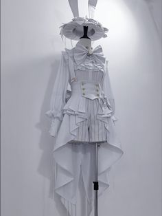 a white dress with long sleeves and ruffles on the skirt is hanging up against a wall