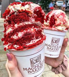 two red velvet desserts are being held up in front of each other with white frosting