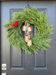 a wreath with bells and evergreen leaves on the front door is adorned with a cardinal