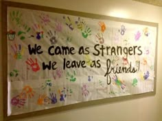 a sign hanging on the wall that says we came as strangers we leave as friends