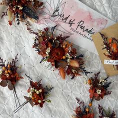 several dried flowers are on a white lace tablecloth with a card in the background