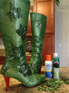 a pair of green boots sitting on top of a counter next to a bottle of cleaner