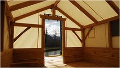 the inside of a building with wooden walls and windows, looking out onto a body of water