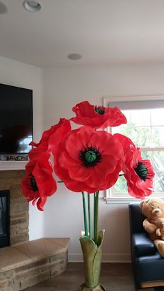 a vase filled with red flowers sitting next to a teddy bear on a black chair