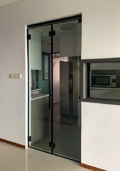 an empty room with a glass door leading into the kitchen