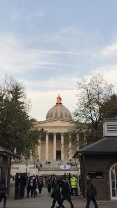 people walking around in front of a building with a dome on it's roof