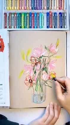 someone is drawing flowers in a vase with colored crayons on the wall behind them