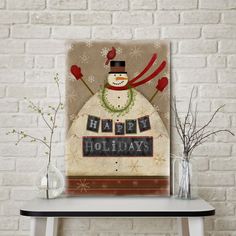 a snowman is sitting in front of a brick wall with the words happy holidays written on it