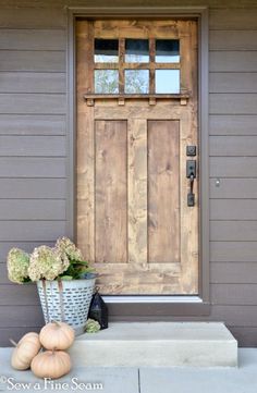 the front door is made out of wood and has two pumpkins on the step