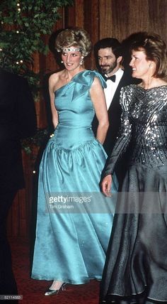 two women in evening gowns and one man in tuxedo standing next to each other