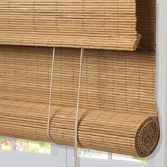 a bamboo wall hanging on the side of a white wall with a rope attached to it