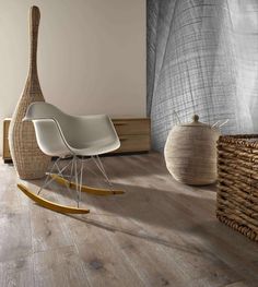 a white rocking chair sitting in front of a window next to a wicker basket