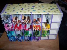 many different colored crayons are lined up on a table with one drawer open