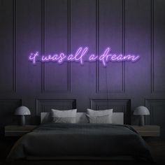 a neon sign that says stay sassy on the wall above a bed in a dark room