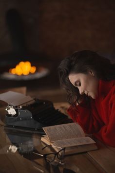 a woman sitting at a table with an open book and typewriter in front of her