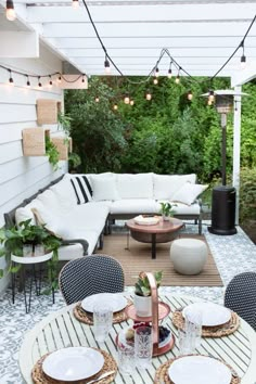 an outdoor patio with white furniture and string lights