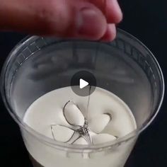 someone is pouring something into a cup with white liquid in it and the lid has an upside down spider on it