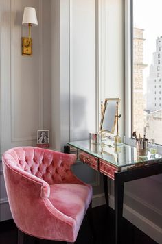 a pink velvet chair sitting in front of a desk