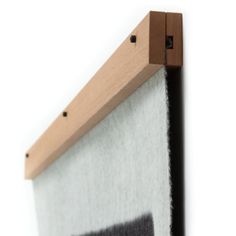 a piece of wood mounted to the side of a white and black wall hanging on a wooden frame