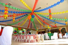 an indoor event decorated with balloons, streamers and tables set up for a party