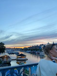 a woman standing on top of a balcony next to a river filled with lots of boats