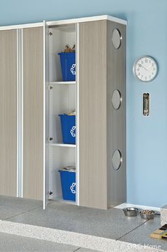 a white and grey cabinet with blue bins next to a clock on the wall