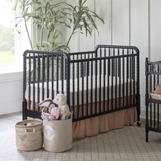 a baby crib with a stuffed animal in it next to a potted plant