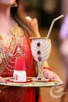 a woman holding a tray with a drink and lipstick on it