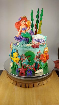 a birthday cake decorated with an image of ariel the mermaid and other disney characters on it