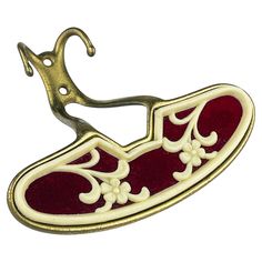 a red and white brooch with a gold hook on it's back end