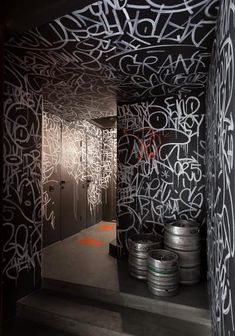 graffiti is painted on the walls in an industrial room with metal barrels lined up against the wall