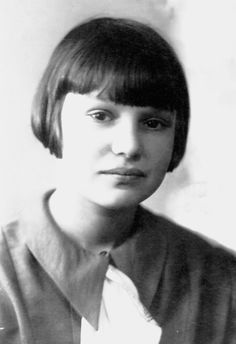 an old black and white photo of a woman with short hair wearing a shirt and tie