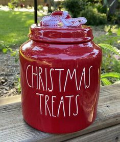 a red jar with the words christmas treats written on it sitting on a wooden bench