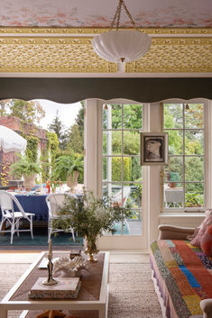 a living room filled with furniture and lots of windows next to a patio covered in plants