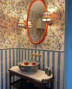 a bathroom sink sitting under a mirror in front of a wall mounted faucet