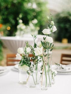 three vases filled with white flowers sitting on top of a table